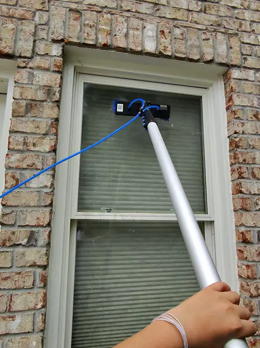 Cleaning a double hung window on a brick home with a water fed pole