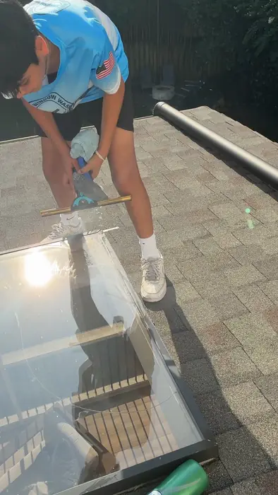 Step 4, Detail and walkaround: Crew member in a Kash's Window Washing shirt cleaning glass by hand