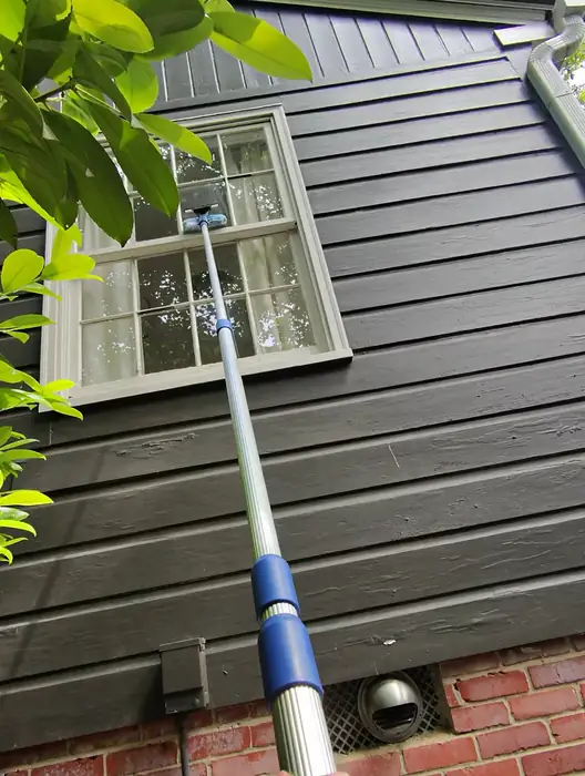 Cleaning second story windows on dark siding with a pole