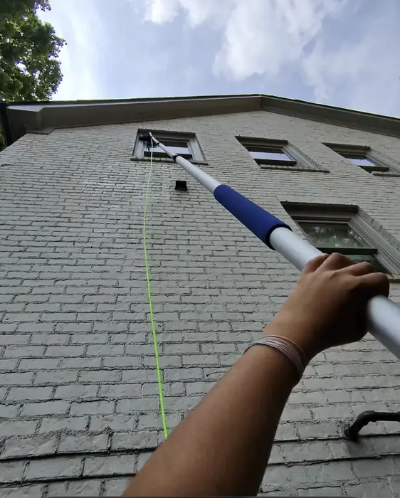 Looking up a water fed pole cleaning second story windows on a brick home