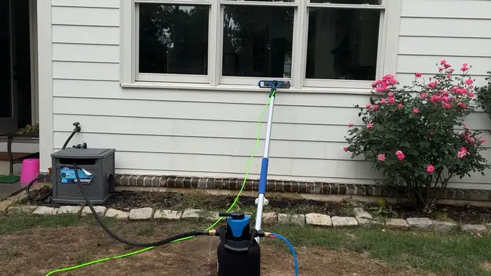 Water fed pole at a window next to a rose bush, with the water tank