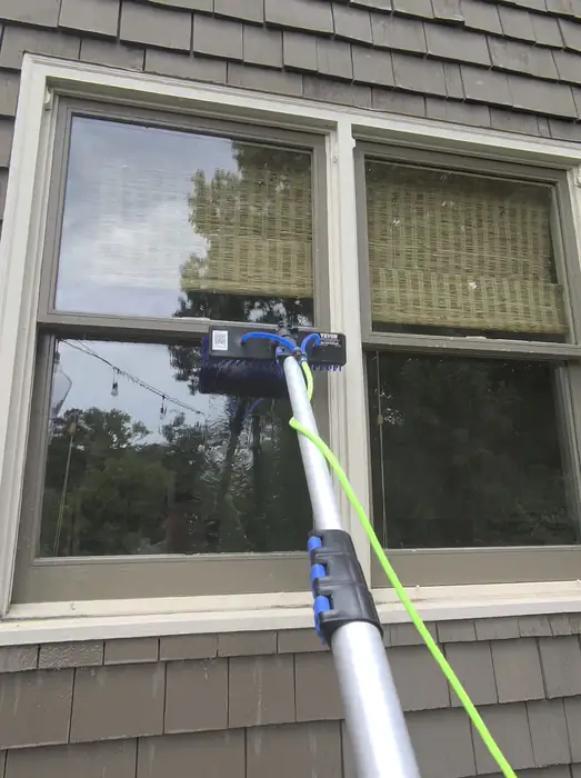 Water fed pole brush cleaning windows on a shingle sided home